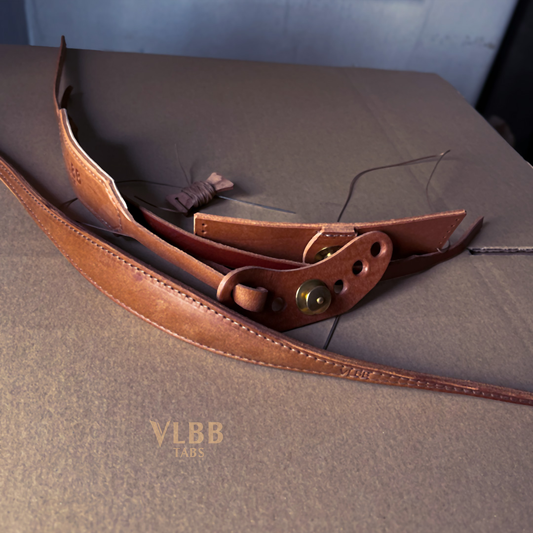 Leather bow sling with laced riser wrap and brass button, made to measure