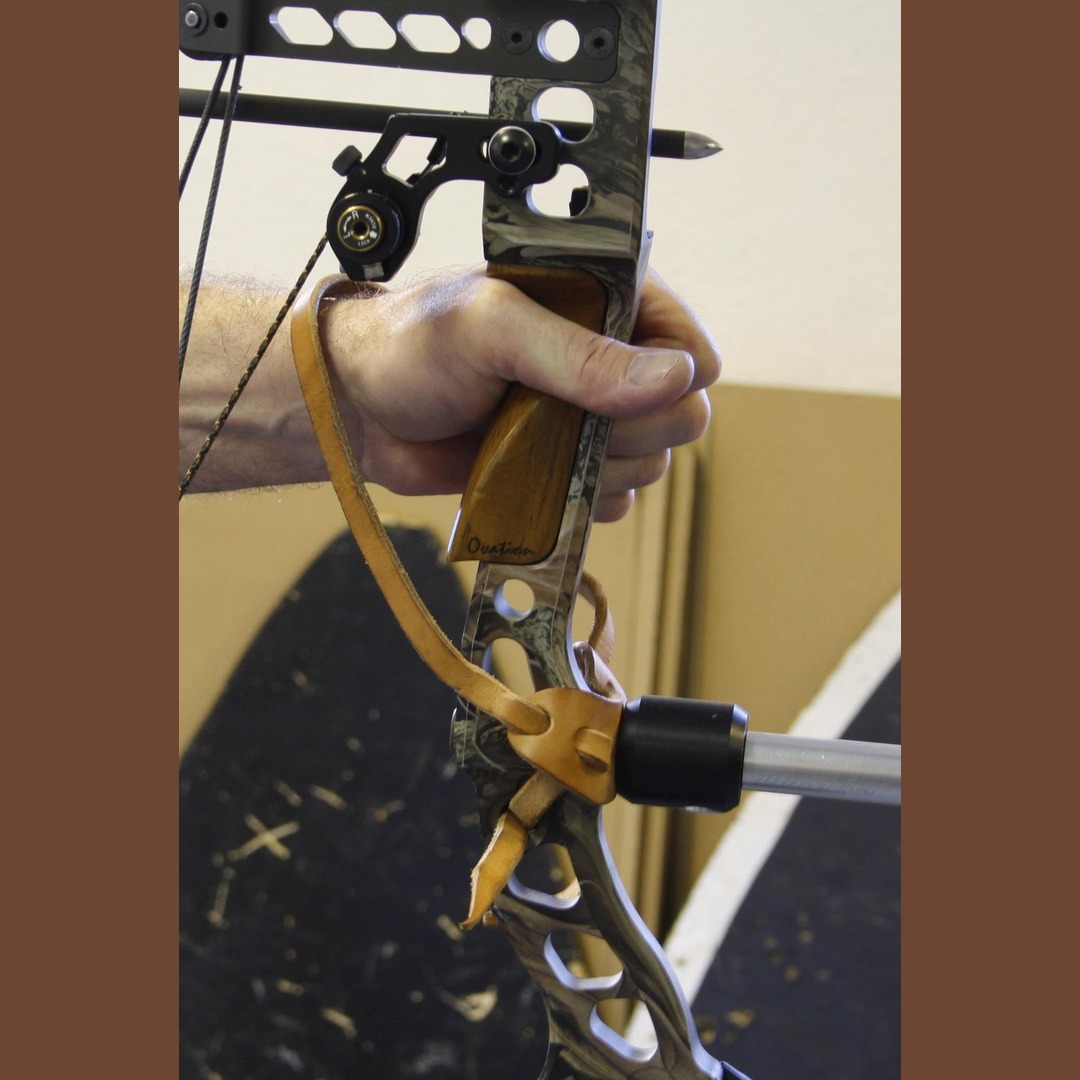 Leather bow sling on a recurve riser, the leather base clamped under the stabiliser